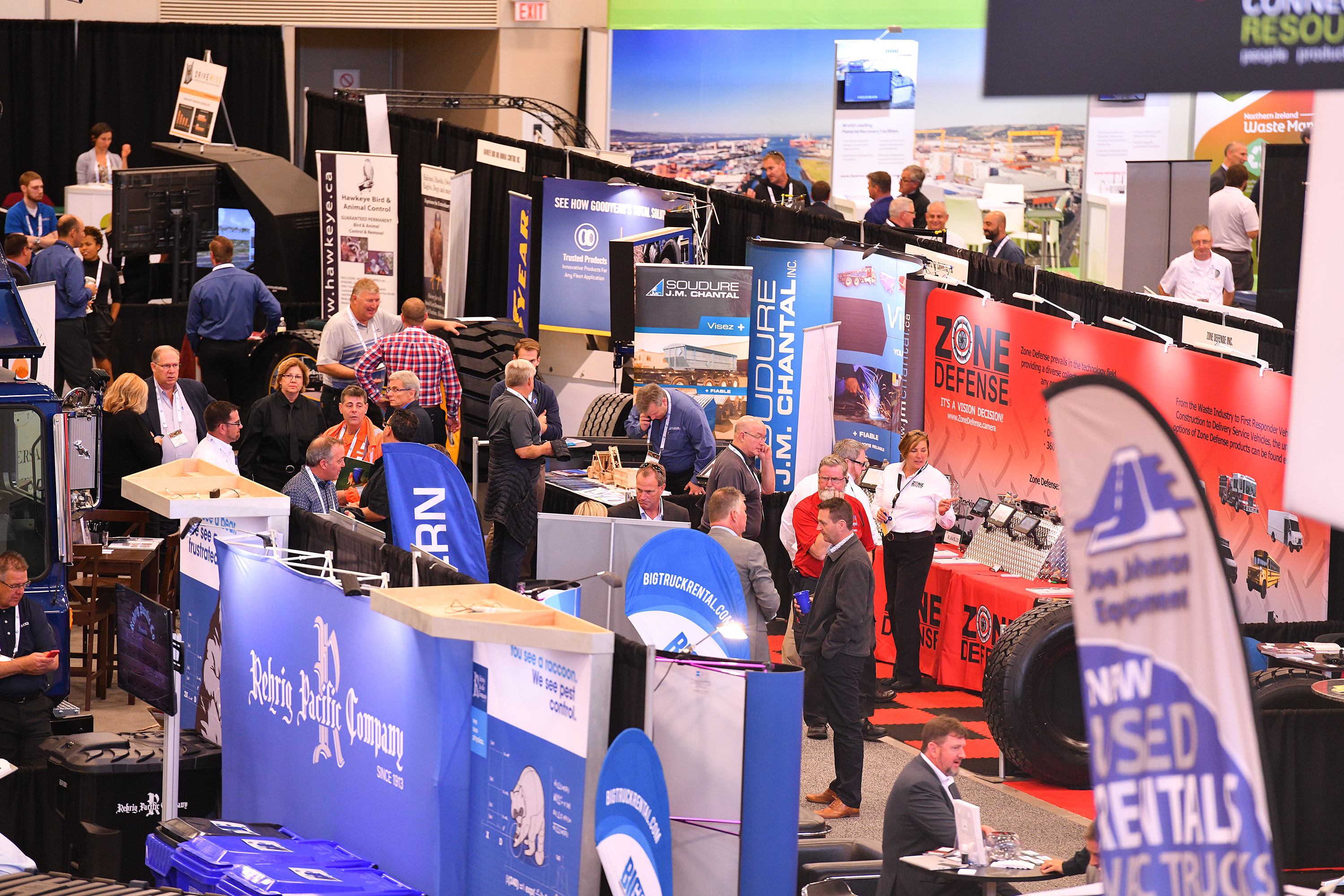 Attendees and exhibitors interacting at a trade show with various company booths and displays, showcasing products and services at Messe Frankfurt North America event.